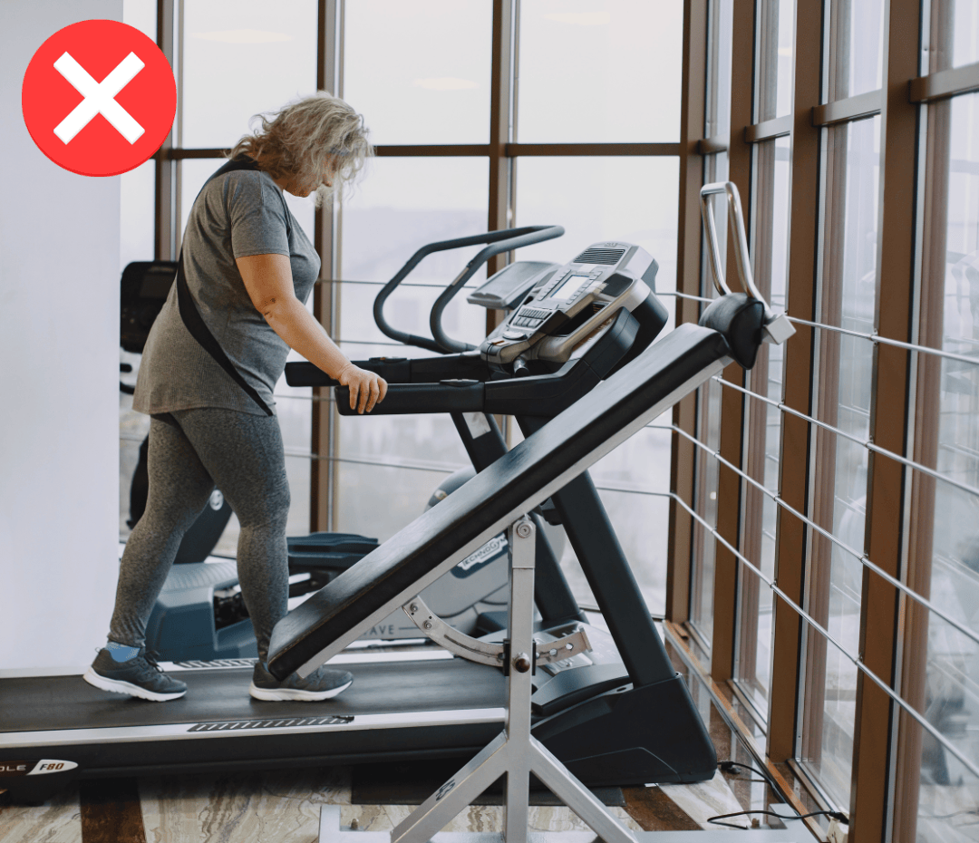 Woman over 50 struggling on a treadmill at a big gym, highlighting why generic cardio machines often don’t work for improving strength and mobility after 50.